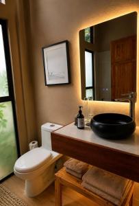 a bathroom with a sink and a toilet and a mirror at KAÑIK APART HOTEL in Puerto Viejo +21 photos