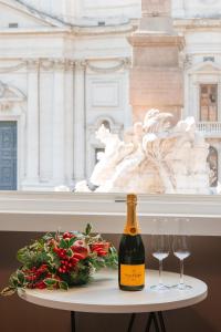 una botella de champán y dos copas de vino en una mesa en Rhea Silvia Luxury Navona en Roma
