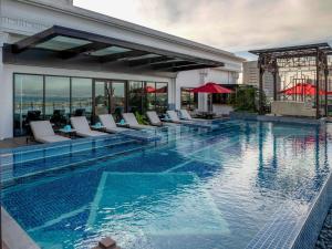 a swimming pool with chairs and a building at Admiral Hotel Manila - MGallery Collection in Manila