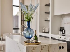 a table with a blue vase and a bottle of wine at Zilte Watervilla in Kamperland +27 photos