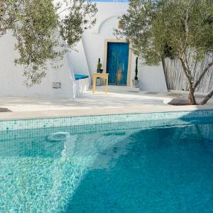 a blue swimming pool with a table and a blue door at Menzel LellaMina in Houmt Souk