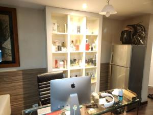 an apple computer on a glass desk with a refrigerator at The Greenway Sukhumvit 50 in Phra Khanong
