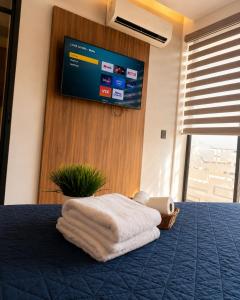 a bed with a blanket and a tv on the wall at DG Comfort - Depart Privado con balcon in Villahermosa