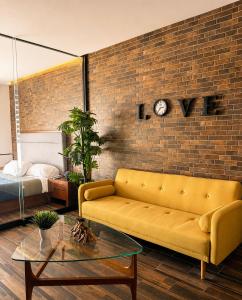 a living room with a yellow couch and a brick wall at DG Comfort - Depart Privado con balcon in Villahermosa