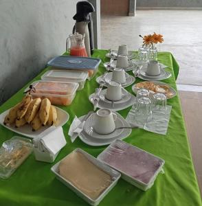 a table with a green table cloth with food on it at Pousada Posto Junior - Madalena CE in Madalena +1 photo