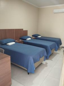 two beds in a room with blue sheets at Pousada Posto Junior - Madalena CE in Madalena