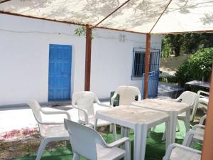 a group of white tables and chairs under an umbrella at El cortijo azul in Güéjar-Sierra