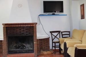 a living room with a fireplace and a flat screen tv at El cortijo azul in Güéjar-Sierra +43 photos