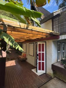 a porch of a house with a red and white door at Chalé cercado pela natureza in Imbituba