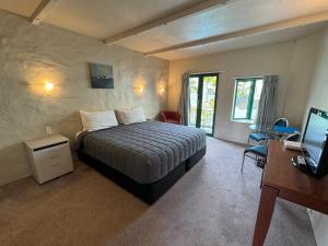 a bedroom with a bed and a desk and a television at Parklane Motor Lodge in Auckland