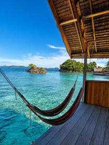 a hammock on a deck with a view of the ocean at Gloria Dive Homestay in Keruo