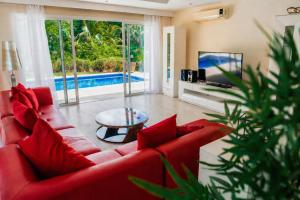 a living room with a red couch and a tv at Private Iberosta Villa Lagoon 4BDR- Private Beach and Pool in Punta Cana