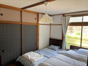 a bedroom with a bed and a window at HOTEL DanDan in Shuzenji