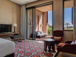 a room with a living room with a couch and a tv at Fairmont Royal Palm Marrakech in Marrakesh