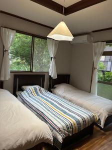 two beds in a room with a window at HOTEL DanDan in Shuzenji