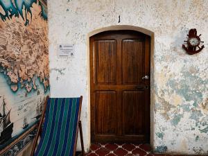 a wooden door with a chair next to a wall at Amura Hostel - Antigua Guatemala in Antigua Guatemala
