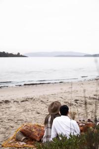 two people sitting on the beach looking at the ocean at VeraLuna in Garden Island Creek