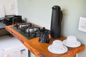 a counter top with a stove and some cups and plates at Refúgio na Mata Atlântica com Ofurô Aquecido in Ubatuba