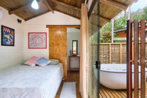 a bedroom with a bed and a bath tub at Refúgio na Mata Atlântica com Ofurô Aquecido in Ubatuba