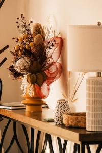 a table with a lamp and a vase with flowers on it at VeraLuna in Garden Island Creek