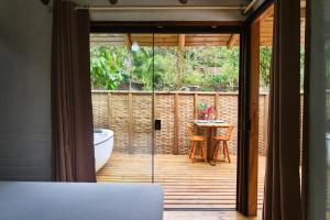 a sliding glass door leading to a patio with a table at Refúgio na Mata Atlântica com Ofurô Aquecido in Ubatuba +36 photos