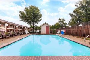 a large blue swimming pool with chairs and a fence at Highland Inn in Arlington