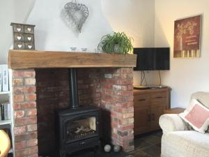 a living room with a brick fireplace with a stove at Brookvale Cottage in Downpatrick