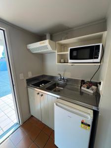 a small kitchen with a sink and a microwave at Parklane Motor Lodge in Auckland