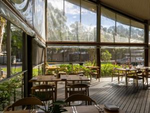 a restaurant with tables and chairs and large windows at NRMA Angourie Resort, Yamba in Yamba