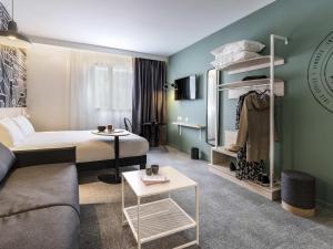 a hotel room with a bed and a couch at ibis Styles Limoges Centre in Limoges