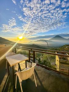 a table and chairs on a balcony with a view at Zambrud Villa Dieng in Kejajar