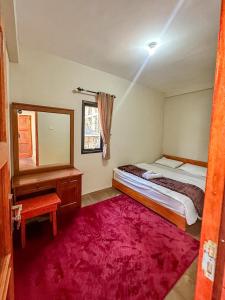 a bedroom with a bed and a mirror and a red rug at Zambrud Villa Dieng in Kejajar