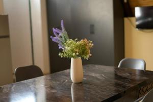 a white vase with purple flowers on a table at Ismayilli in İsmayıllı