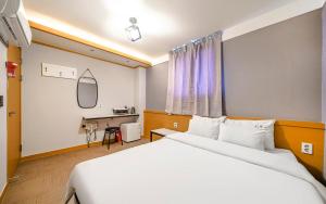a hotel room with two beds and a desk at Osan No25 Hotel in Osan