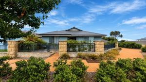 a house with a fence and bushes at Napolean Holiday Retreat in Vasse
