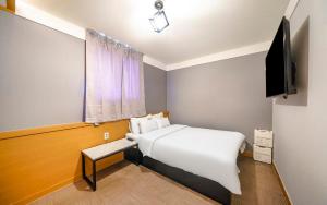 a bedroom with a white bed and a flat screen tv at Osan No25 Hotel in Osan