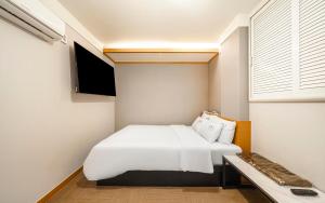 a small bedroom with a white bed and a window at Osan No25 Hotel in Osan