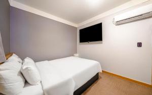 a bedroom with a white bed and a flat screen tv at Osan No25 Hotel in Osan
