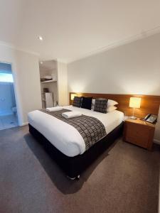 a bedroom with a large bed with white sheets and pillows at Red Earth Motel in Broken Hill +23 photos