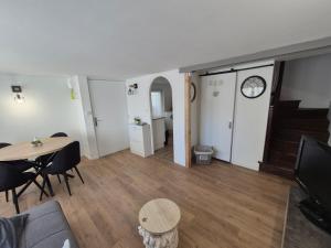 a living room with a table and chairs and a clock at Le cocon en ville in Limoux +8 photos