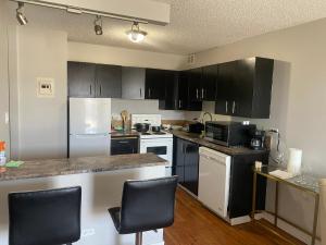 a kitchen with black cabinets and white appliances at Bold property in Calgary