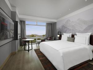 a bedroom with a large white bed and a large window at Swissôtel Clark Philippines in Clark +96 photos