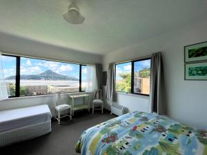 a bedroom with a bed and windows with a view at Seaview Lodge in Tairua