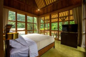 a bedroom with a bed and a large window at The Villa Lululu in Tabanan