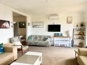 a living room with a couch and a tv at Seaview Lodge in Tairua