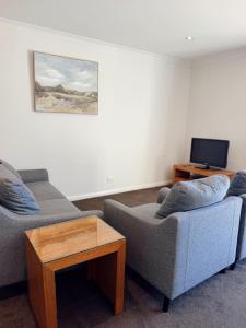 a living room with two couches and a tv at Red Earth Motel in Broken Hill