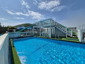 a large swimming pool with a house and a staircase at Daebudo Ara Pension in Ansan +38 photos