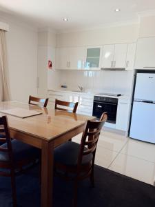 a kitchen with a wooden table and four chairs at Red Earth Motel in Broken Hill