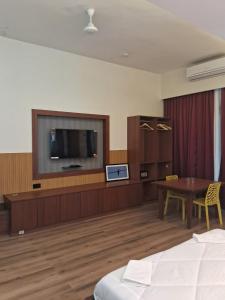 a hotel room with a bed and a tv and a table at Hotel Brindavan Grand in Gulbarga