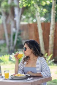 a woman sitting at a table drinking a glass of orange juice at Ecohotel Raices del Rosario in Cartagena de Indias